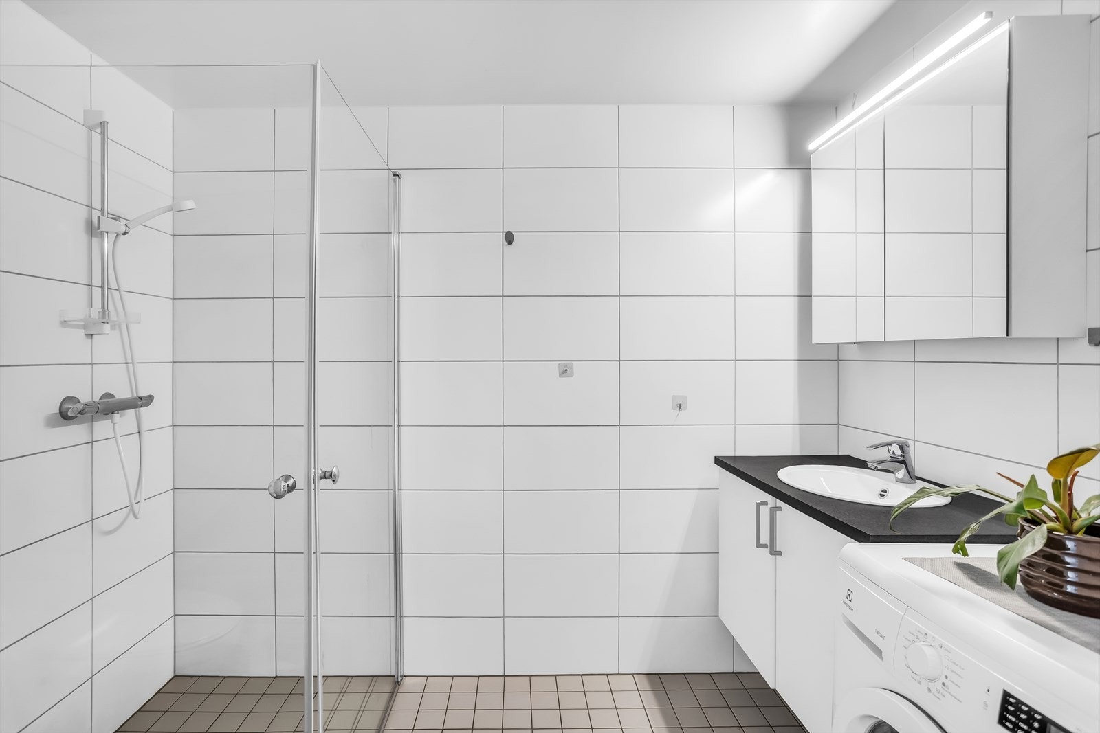 Badet har et stilrent utseende med keramiske fliser og moderne innredning. Galleribilde