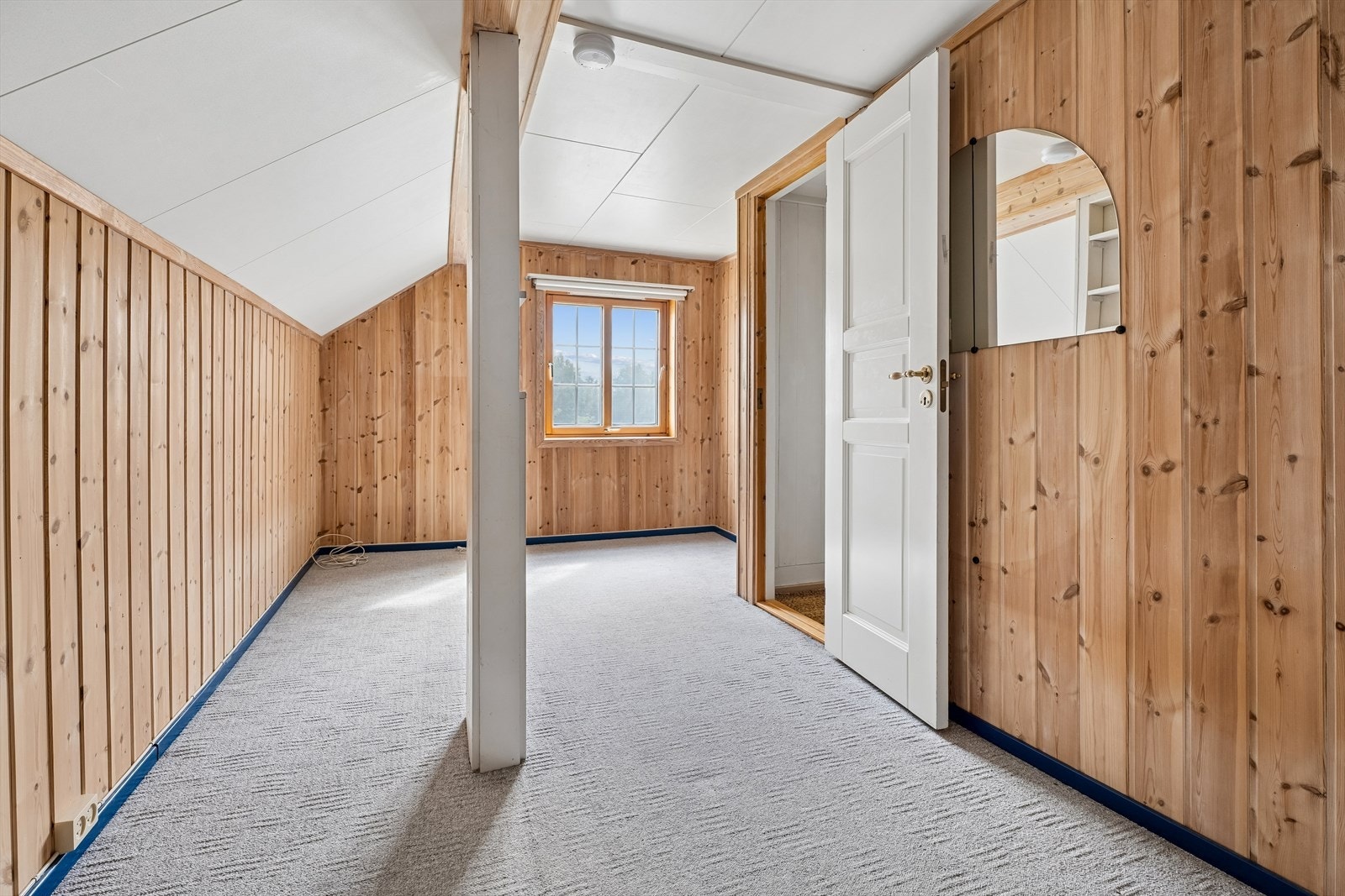 Et av tre soverom i andre etasje, med panelkledde vegger og teppegulv. Galleribilde