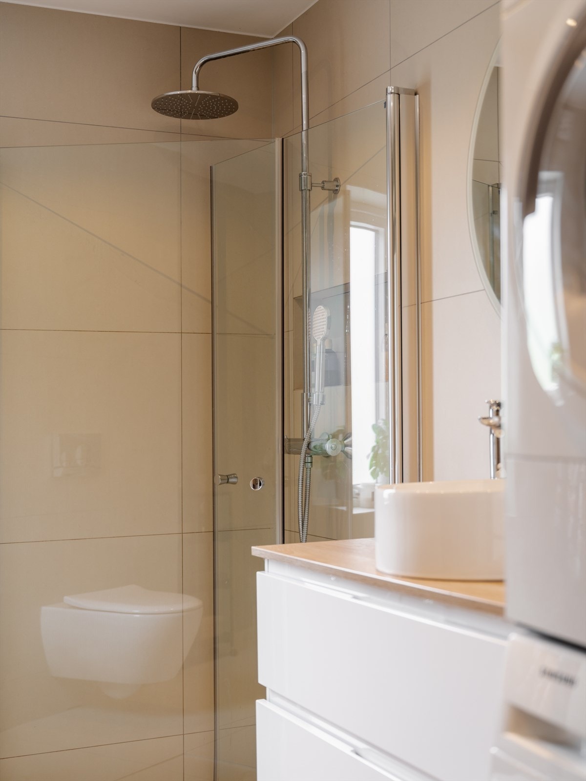 Badet er innredet med vegghengt servantskap, ovenpåliggende servant, speil med lys, vegghengt klosett, dusjhjørne med regn- og hånddusj, og opplegg for vaskemaskin. Galleribilde