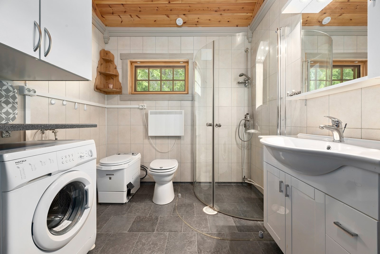 Badet har baderomsplater på veggene og panel i taket, samt vinylbelegg på gulvet. Galleribilde