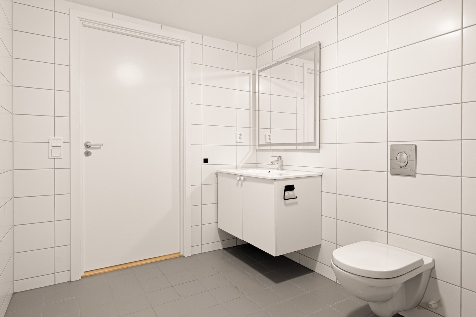 Badet inneholder vegghengt servantinnredning, toalett, dusjhjørne og opplegg for vaskemaskin Galleribilde