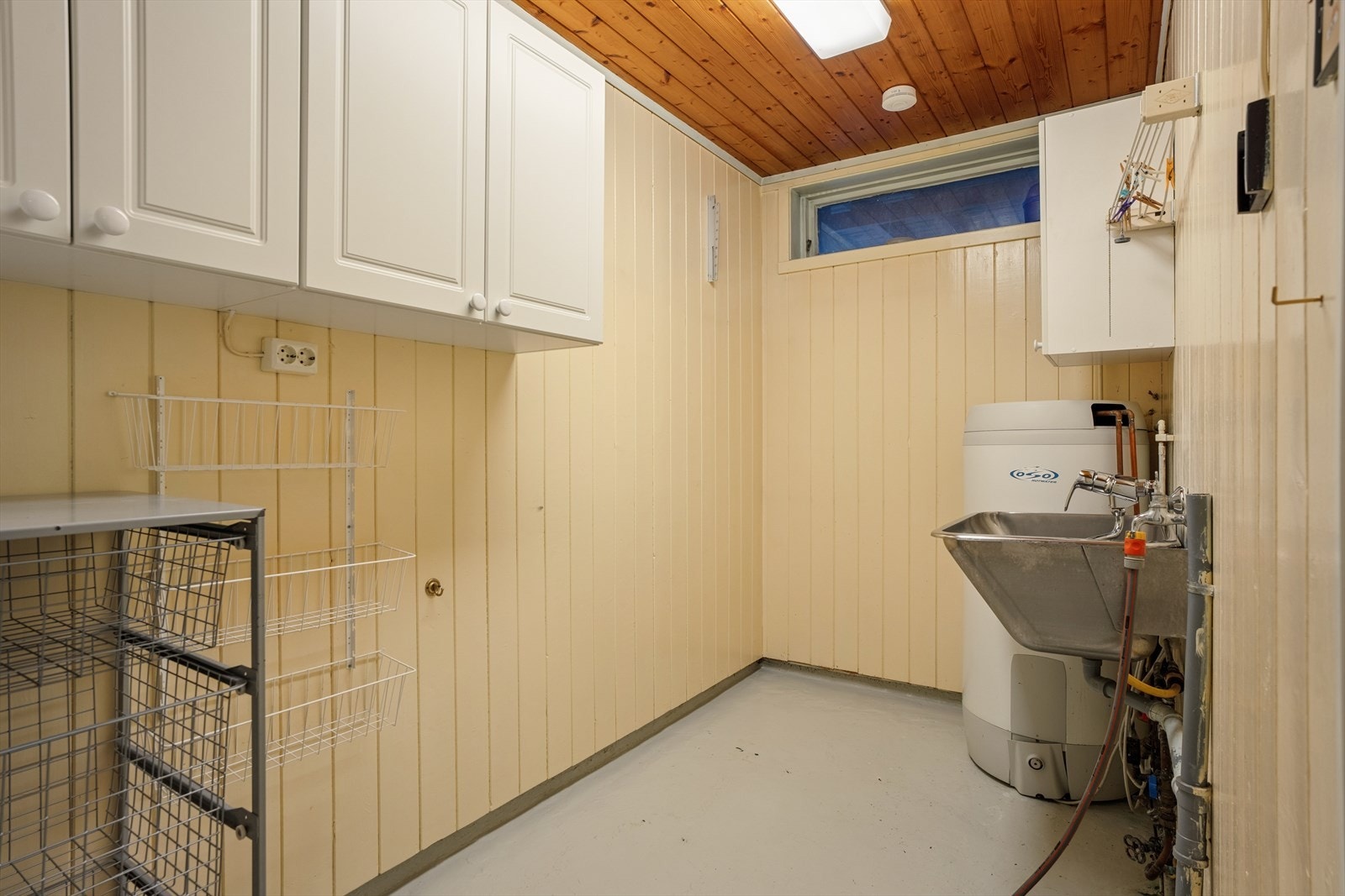 Praktisk vaskerom med opplegg for vaskemaskin, utslagsvask og plass til oppbevaring. Galleribilde