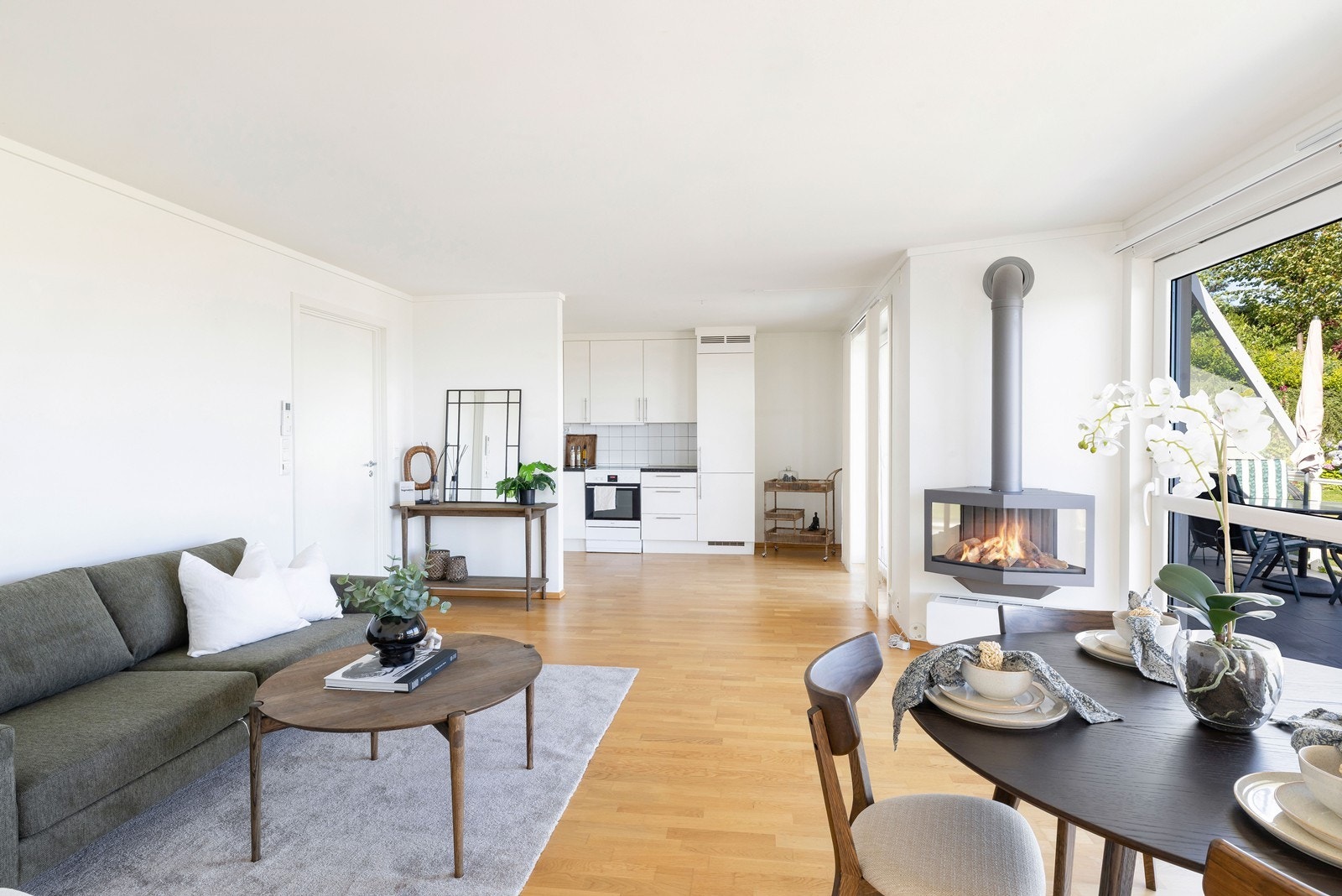 Lys og innbydende stue med åpen løsning mot kjøkkenet og hyggelig gasspeis. Galleribilde