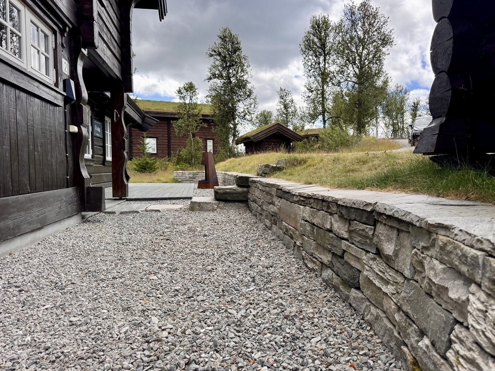 Elegant og solid tørrsteinsmur som rammer inn inngangsparti, adkomst og terrasse på en stilren måte. Galleribilde