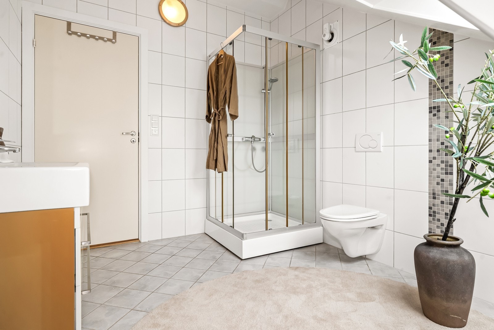 Badet er innredet med vegghengt toalett, dusjkabinett og opplegg for vaskemaskin. Galleribilde