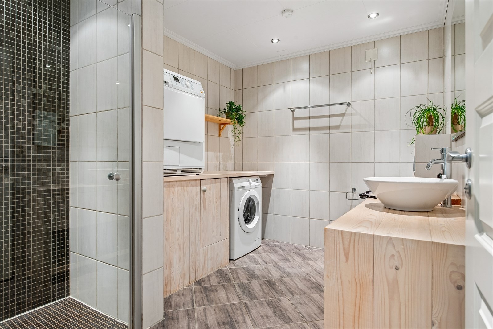 Badet har flislagte overflater, gulvvarme og opplegg for vaskemaskin. Galleribilde