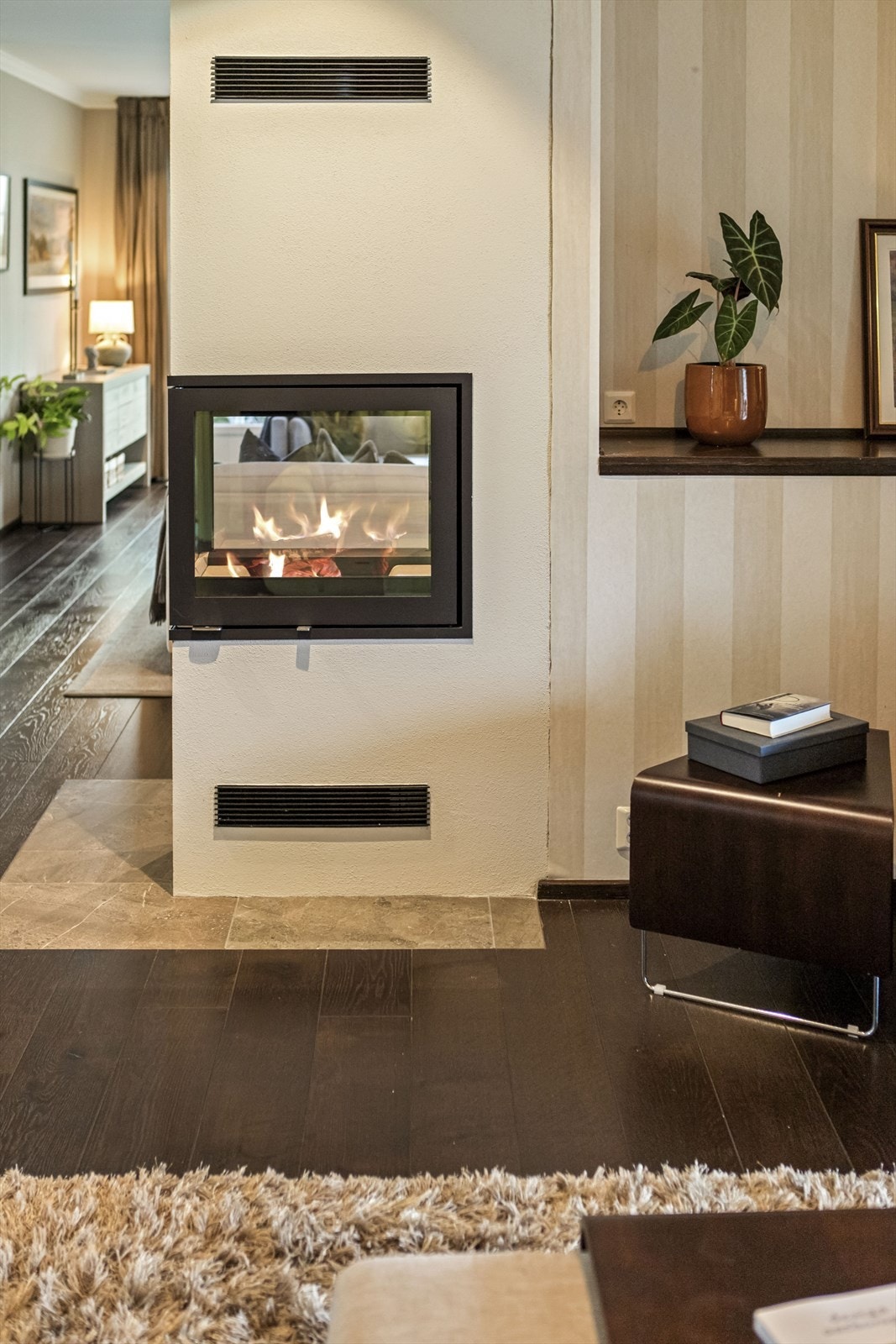 Som et naturlig midtpunkt mellom de ulike stuesonene er det etablert et flott ildsted med glassflater på tre av fire sider. Galleribilde