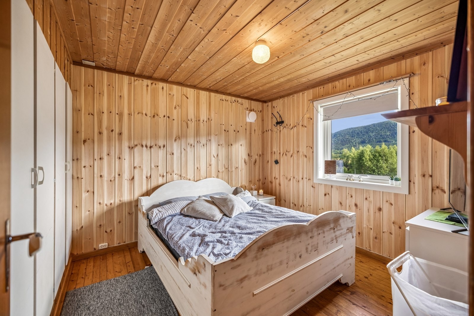Ett av tre soverom i hovedetasjen, med vegger og himling i trepanel. Galleribilde