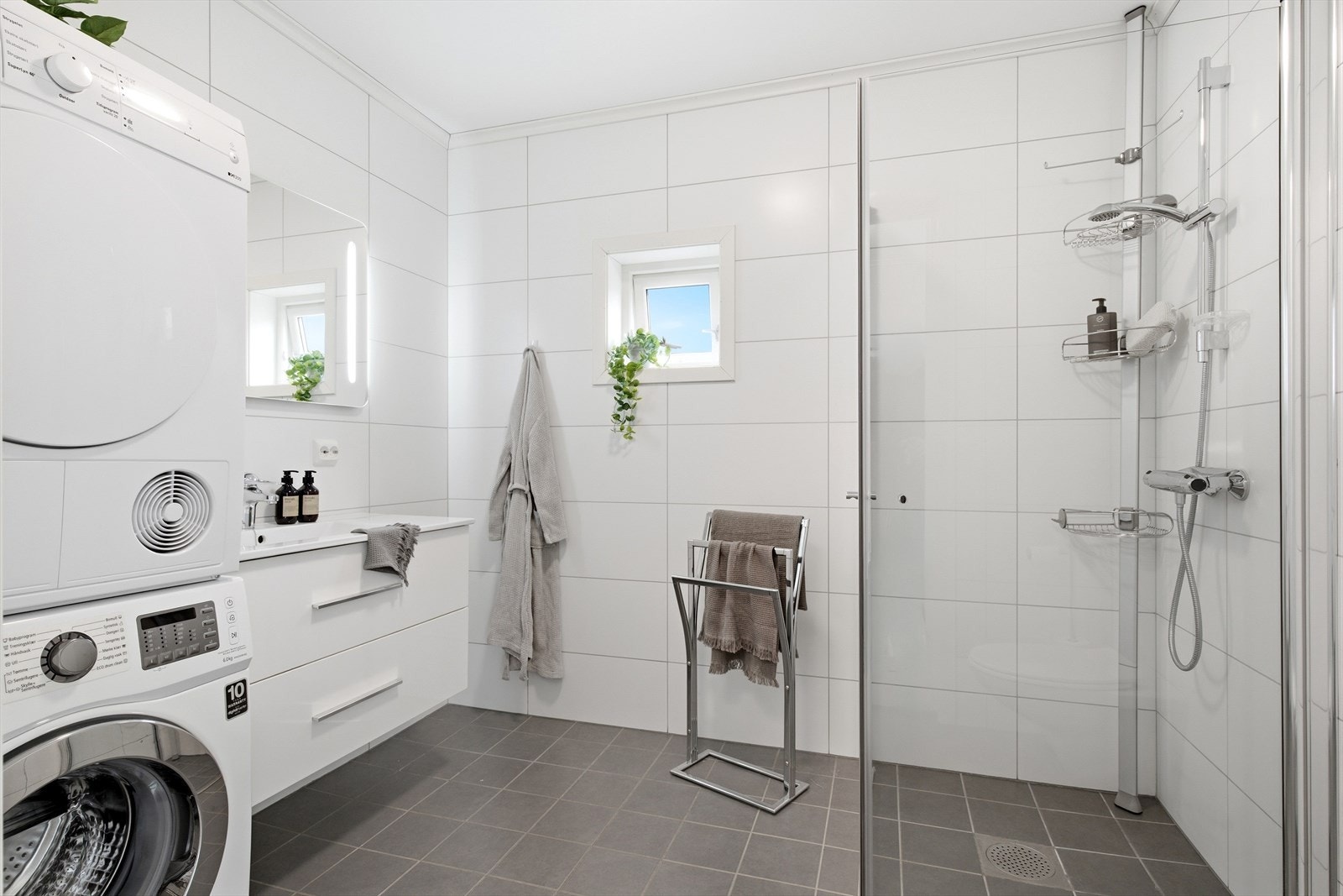 Badet er innredet med dusj med glassdører og vegghengt toalett. Galleribilde