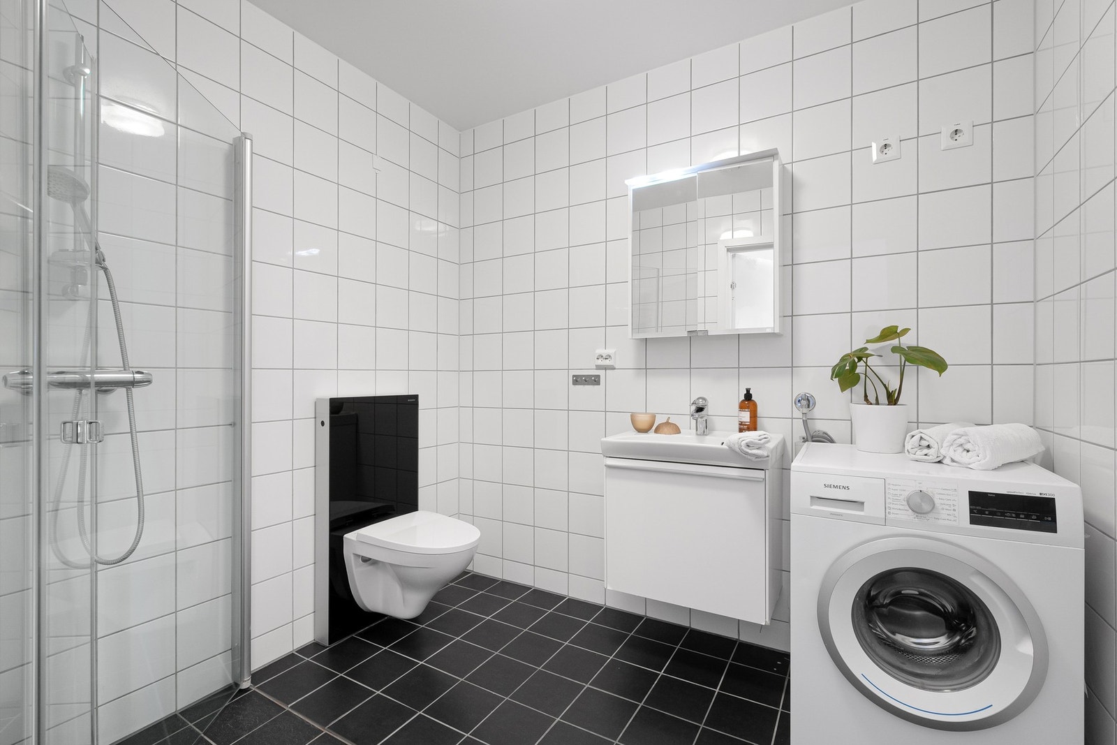 Tidløst helfliset bad med opplegg for vaskemaskin og tørketrommel. Galleribilde