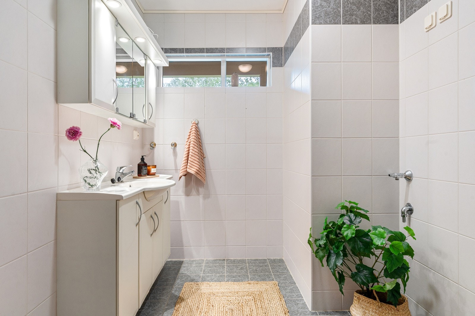 Baderommet er utstyrt med innredning med servant, dusjgarnityr på vegg, samt opplegg til vaskemaskin.