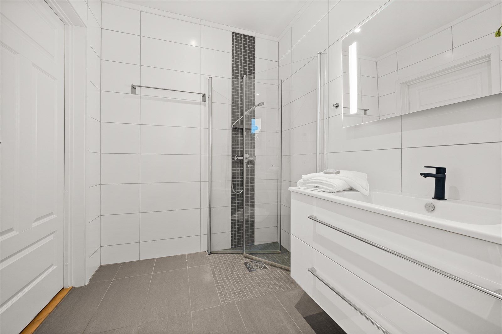 Badet er utstyrt med heldekkende servant med underskap, speil med lys, dusjnisje, toalett og opplegg for vaskemaskin Galleribilde
