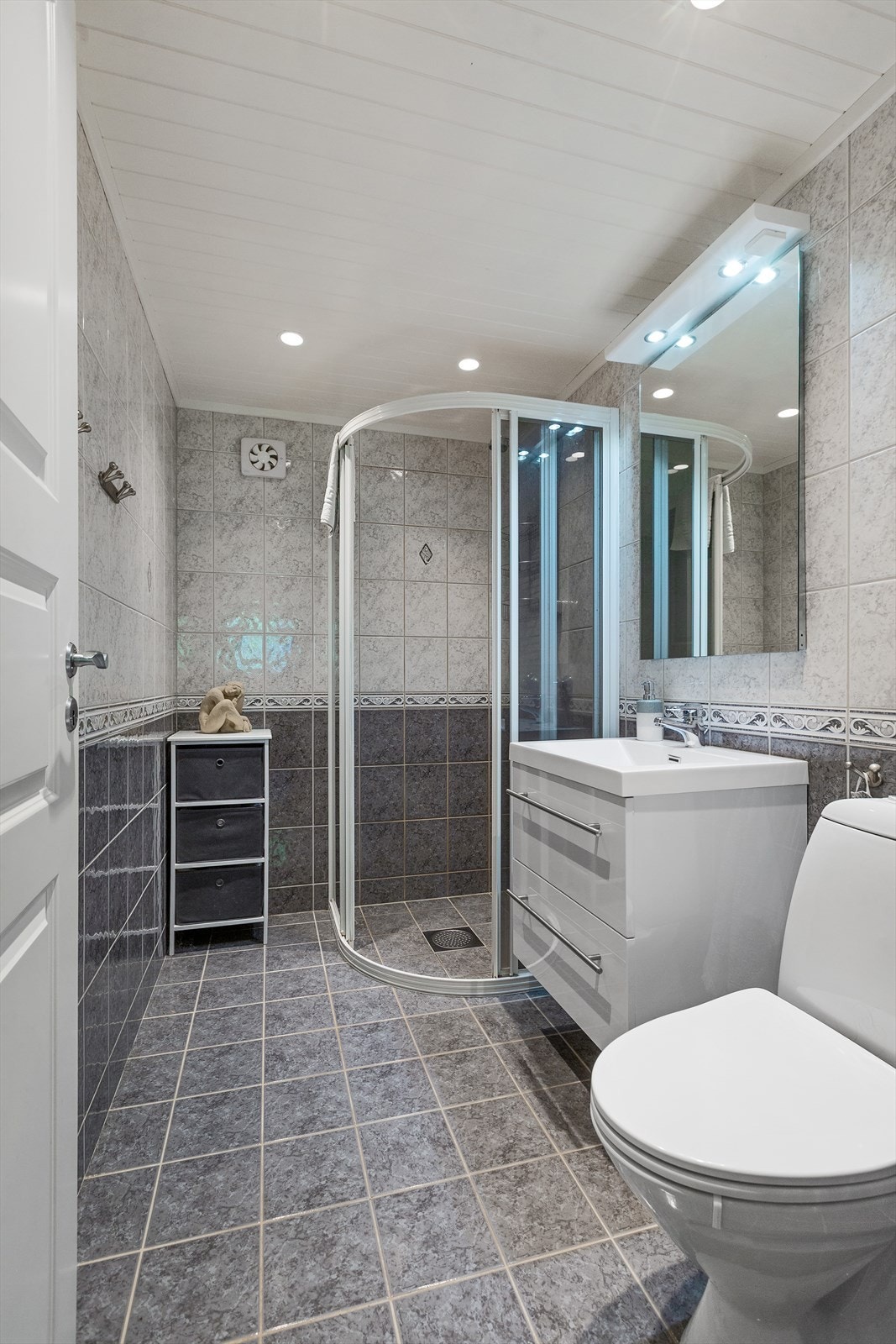Badet har dusjløsning med dusjvegger, toalett og servantinnredning. Galleribilde