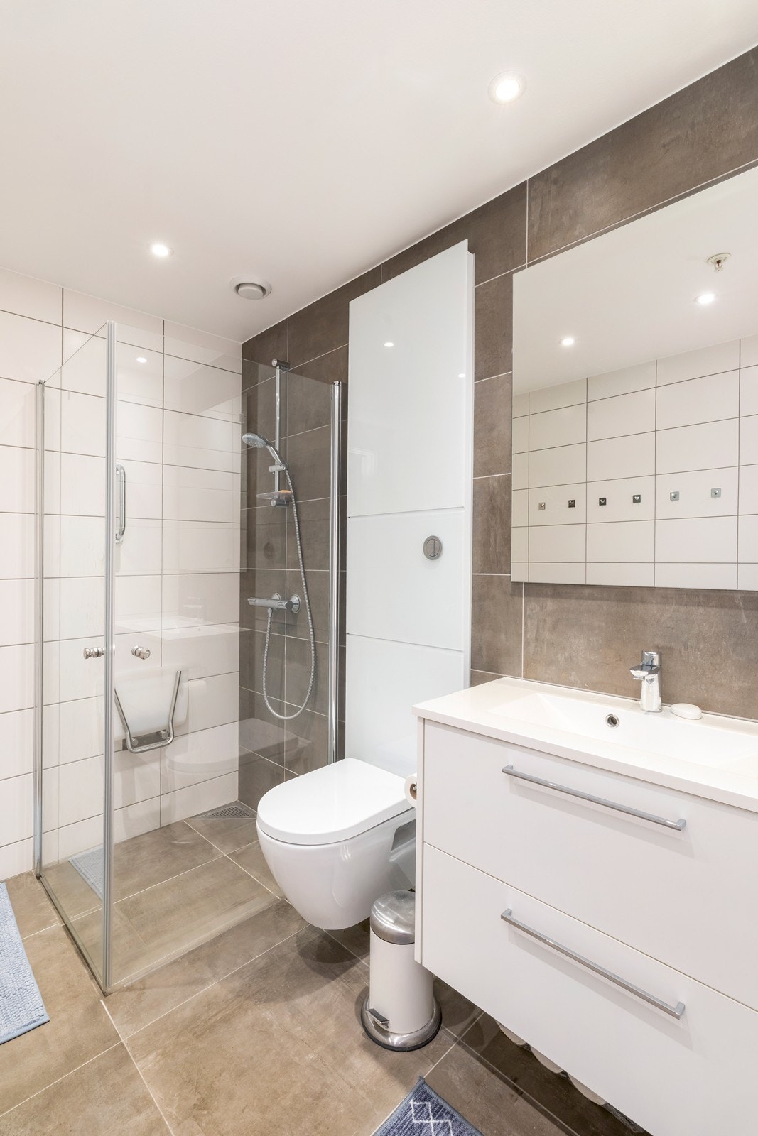 Badet er innredet med vegghengt toalett, dusjnisje og servant med innredning. Galleribilde