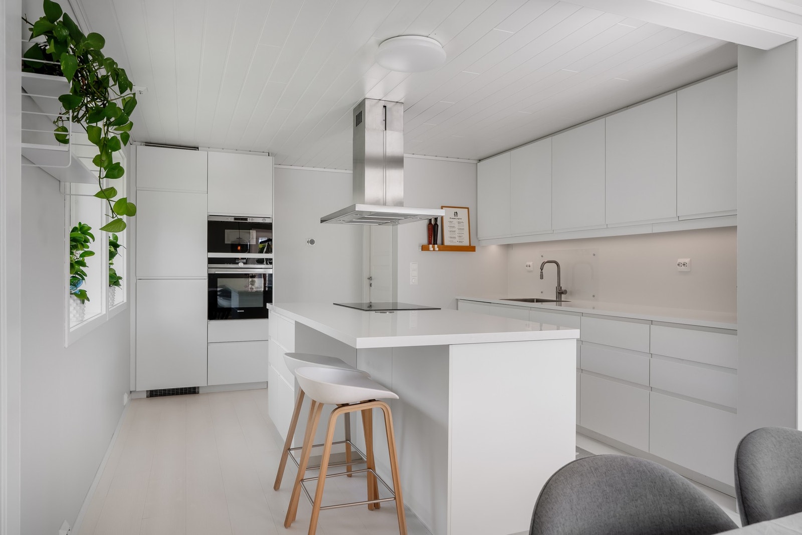 Moderne kjøkken med stilrene fronter, kjøkkenøy og godt med benkeplass. Galleribilde