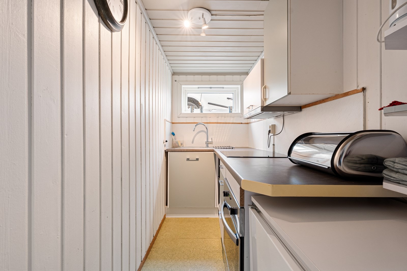 Praktisk kjøkken på 3,8m² med slette fronter og benkeplate i laminat med nedfelt vask. Galleribilde