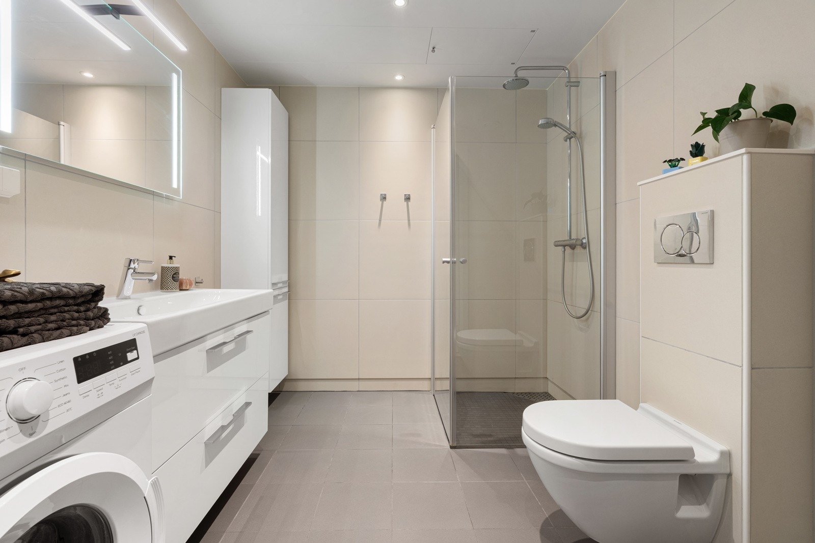 Lekkert bad med delikate storformatfliser. Badet er utstyrt med stor dusjhjørne, praktisk vegghengt toalett og plass for vaskemaskin/tørketrommel.