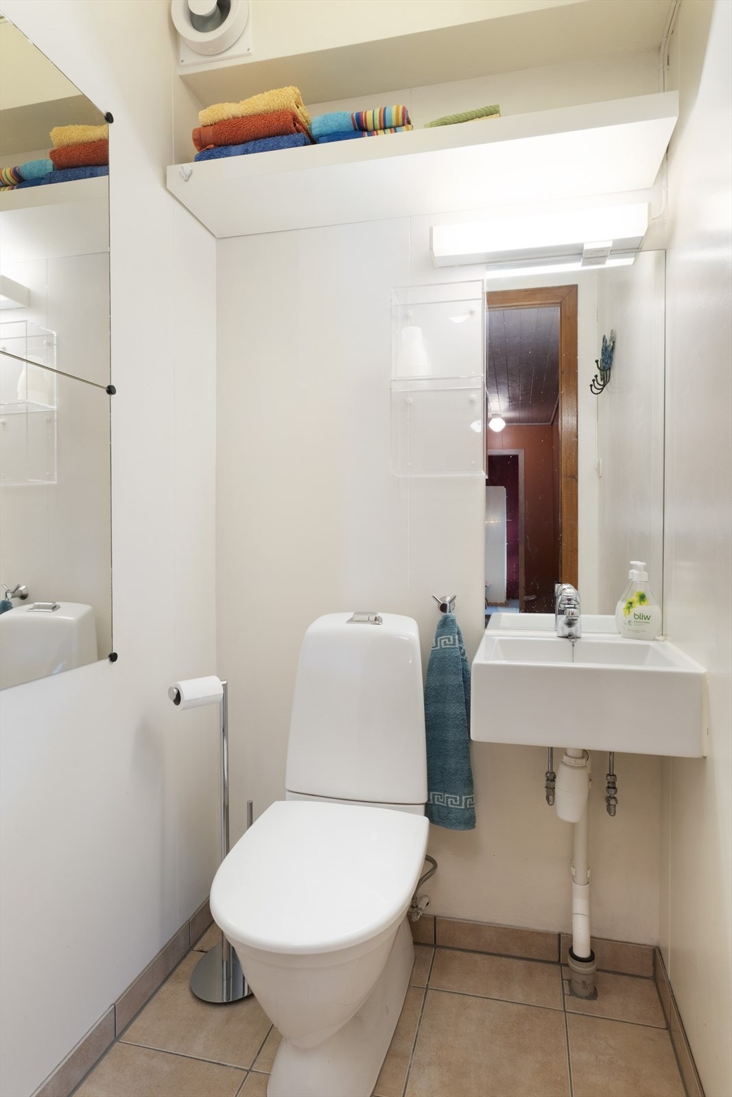 Separat WC har flislagt golv og måla plater på veggane, og er utstyrt med toalett og vegghengd servant. Galleribilde