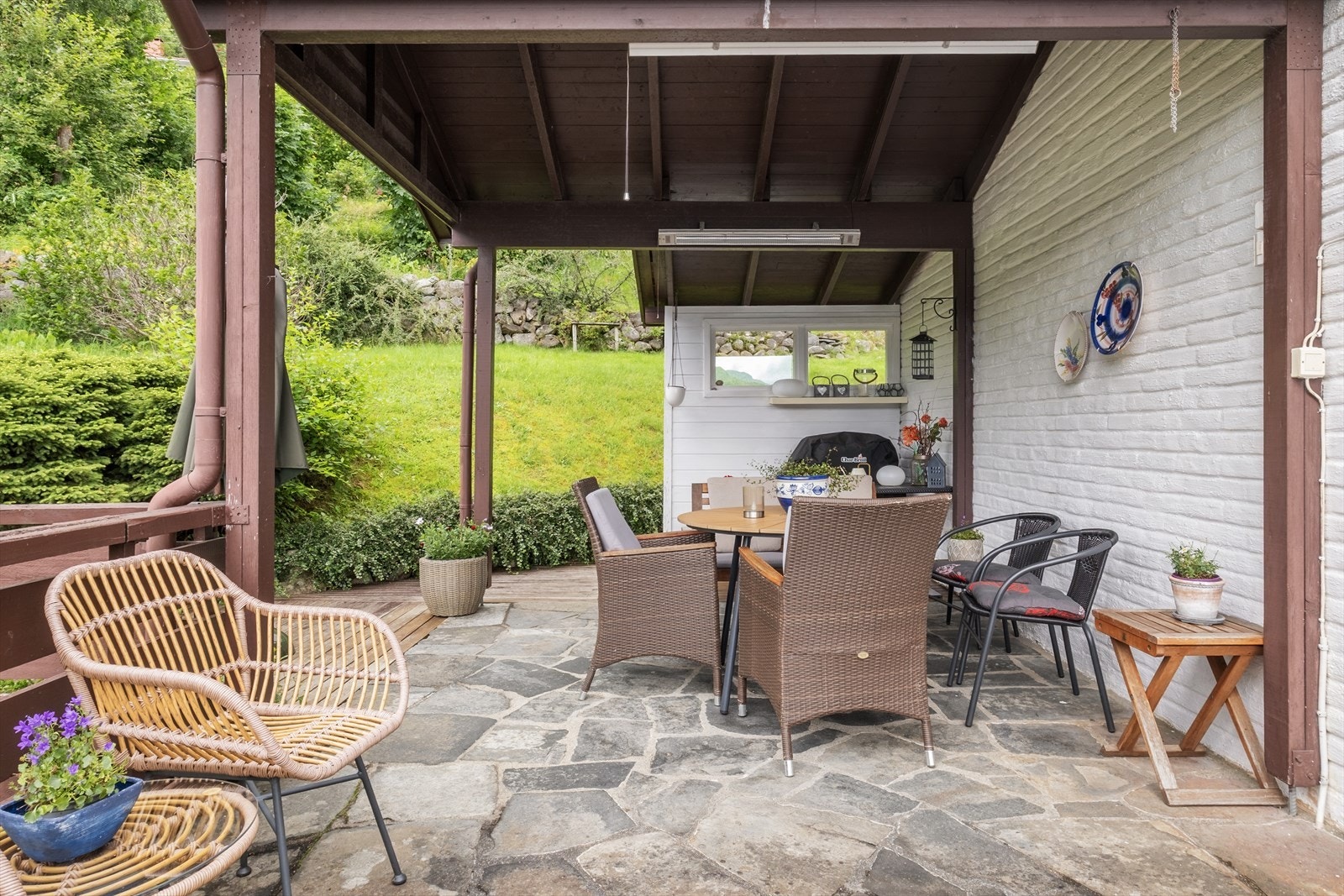 Frå stova er det utgang til ein delvis overbygd terrasse i betongkonstruksjon med nedstøypte heller og rekkverk i tre. Galleribilde