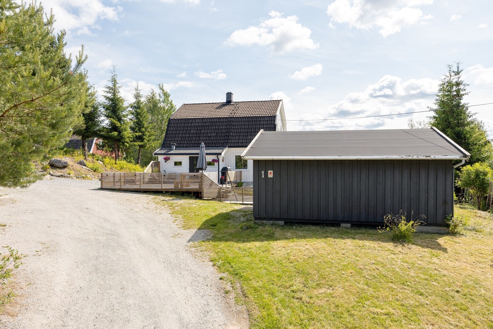 Gårdsplassen er gruset har god plass til flere biler. I tillegg er det to uthus; en innredet med to hestebokser, og en carport Galleribilde