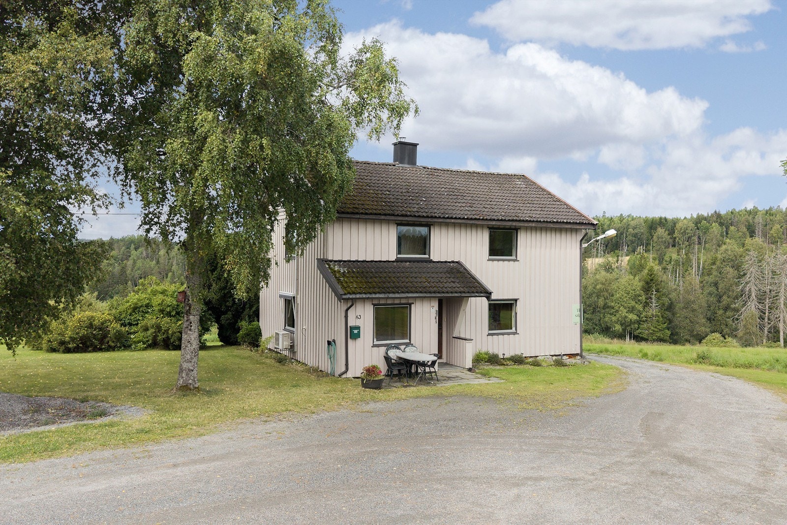 Våningshuset sett fra innkjørselen, med landlige omgivelser. Galleribilde