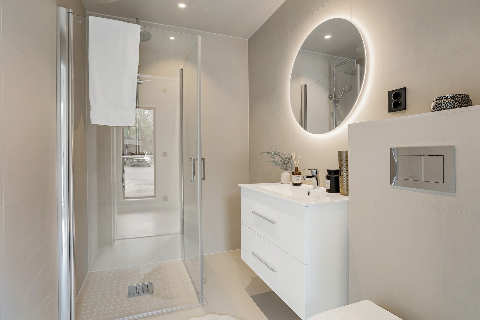 Badet i hovedetasjen er flislagt med delikate fliser på gulv og vegger. Moderne baderomsinnredning med smekkert speil Galleribilde