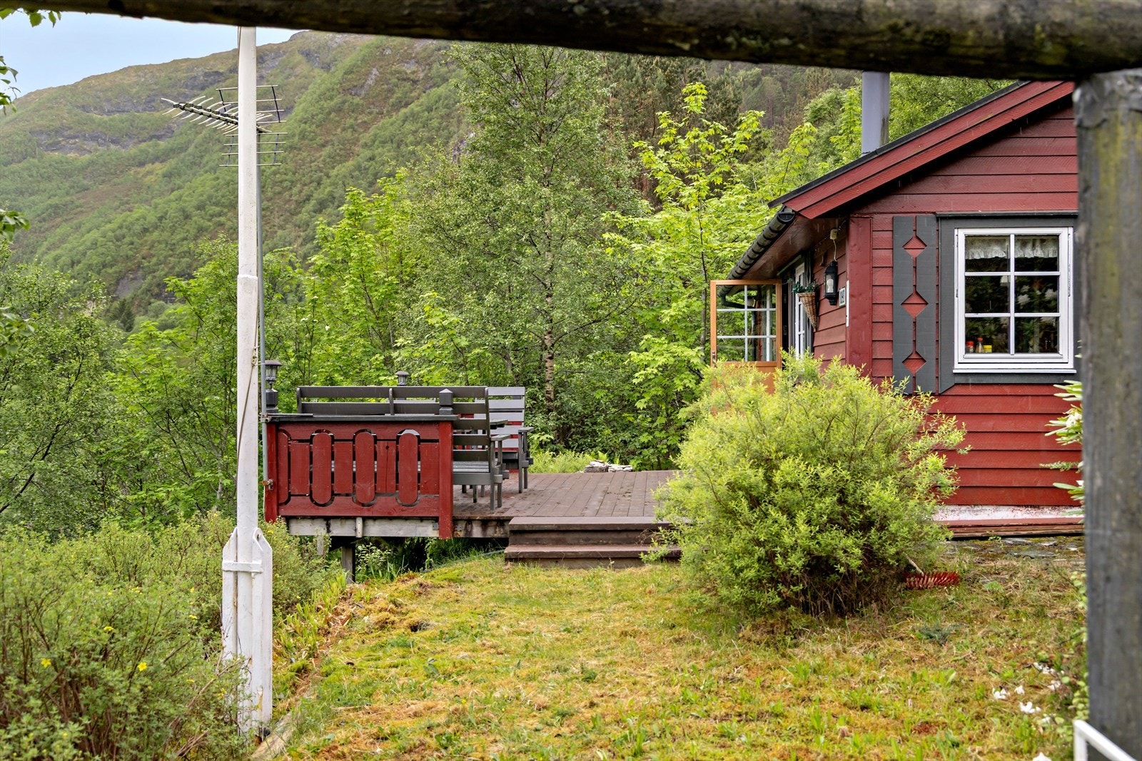Hytta ligg fint til i terrenget med uteplass og natur rundt. Galleribilde