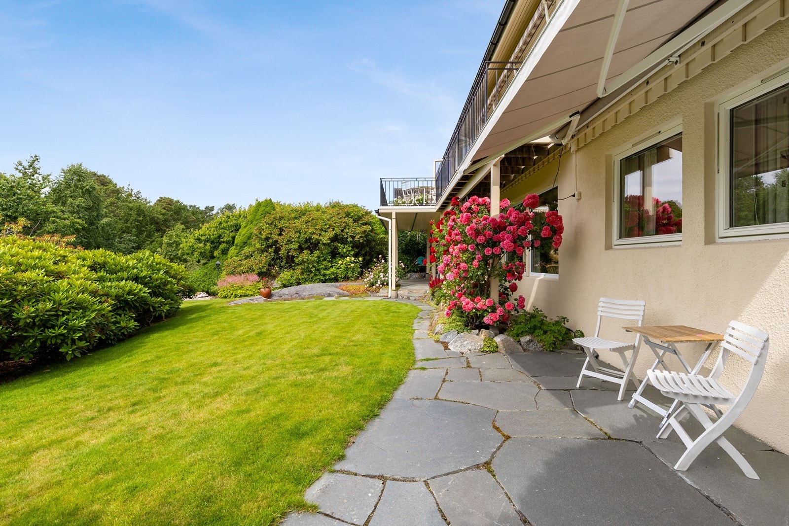 Frodige blomsterbed og velstelte grøntarealer omkranser boligen. Galleribilde