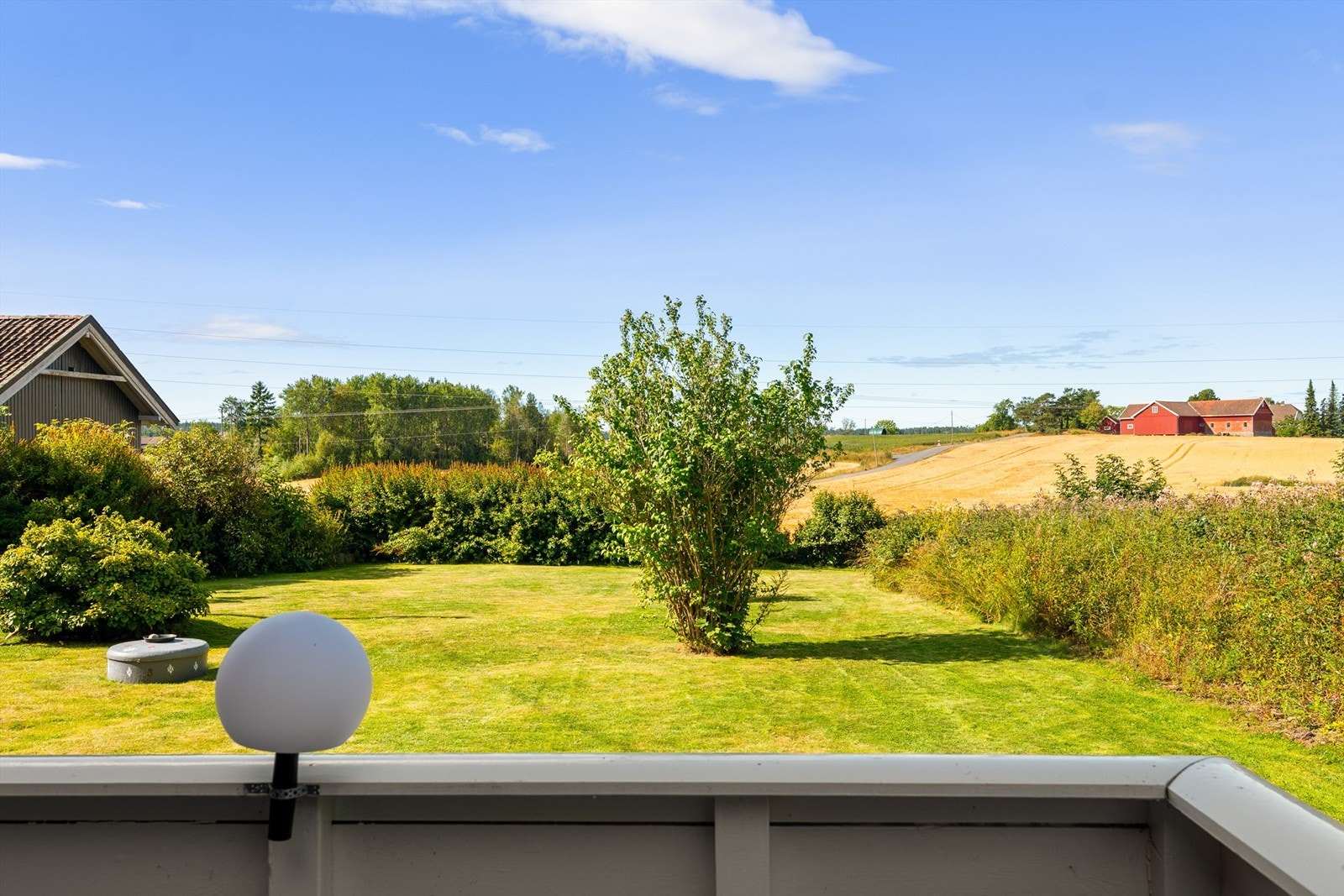 Utsyn fra terrassen, over egen hage og åkerlandskapet i vest. Galleribilde