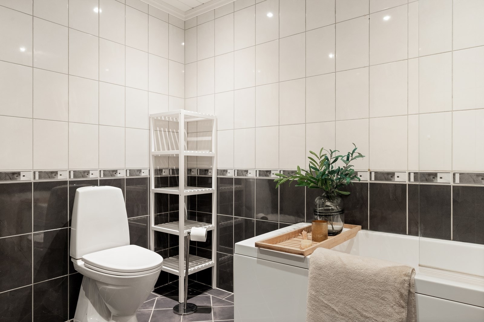 Badet er innredet med gulvstående toalett, servant med skuffer og speilskap. Galleribilde