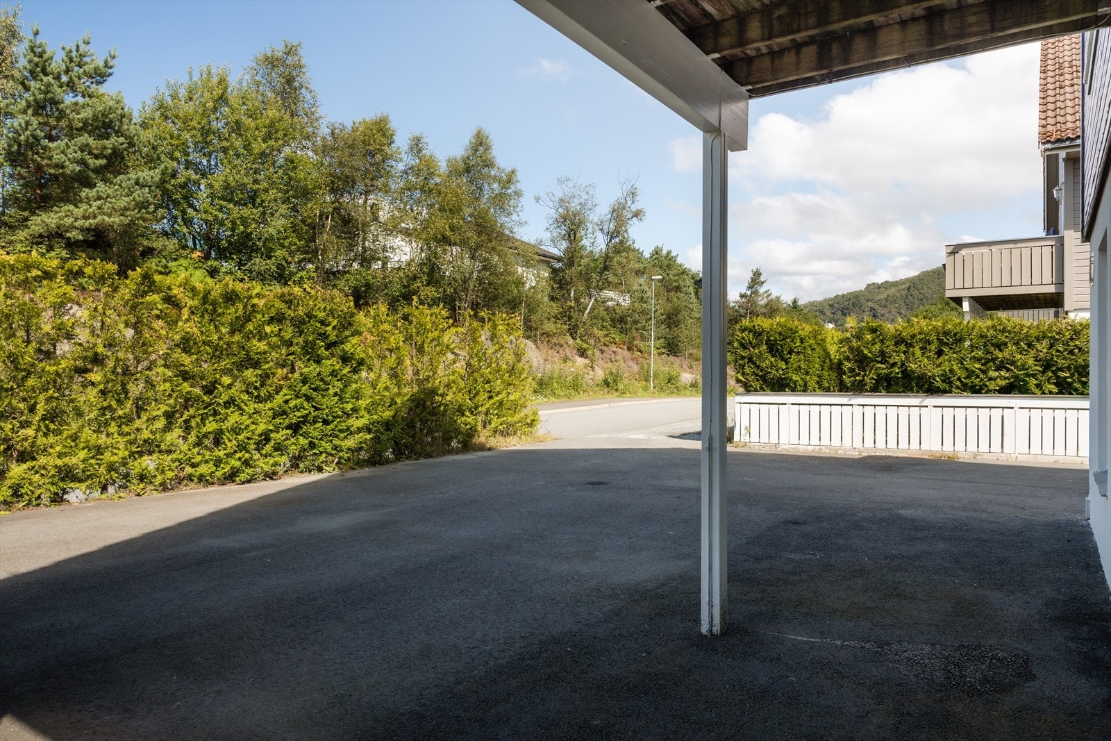Asfaltert gårdsplass med skjermende tujahekk og parkering for opptil fem biler på egen tomt. Sykler kan oppbevares trygt og beskyttet under tak. Galleribilde