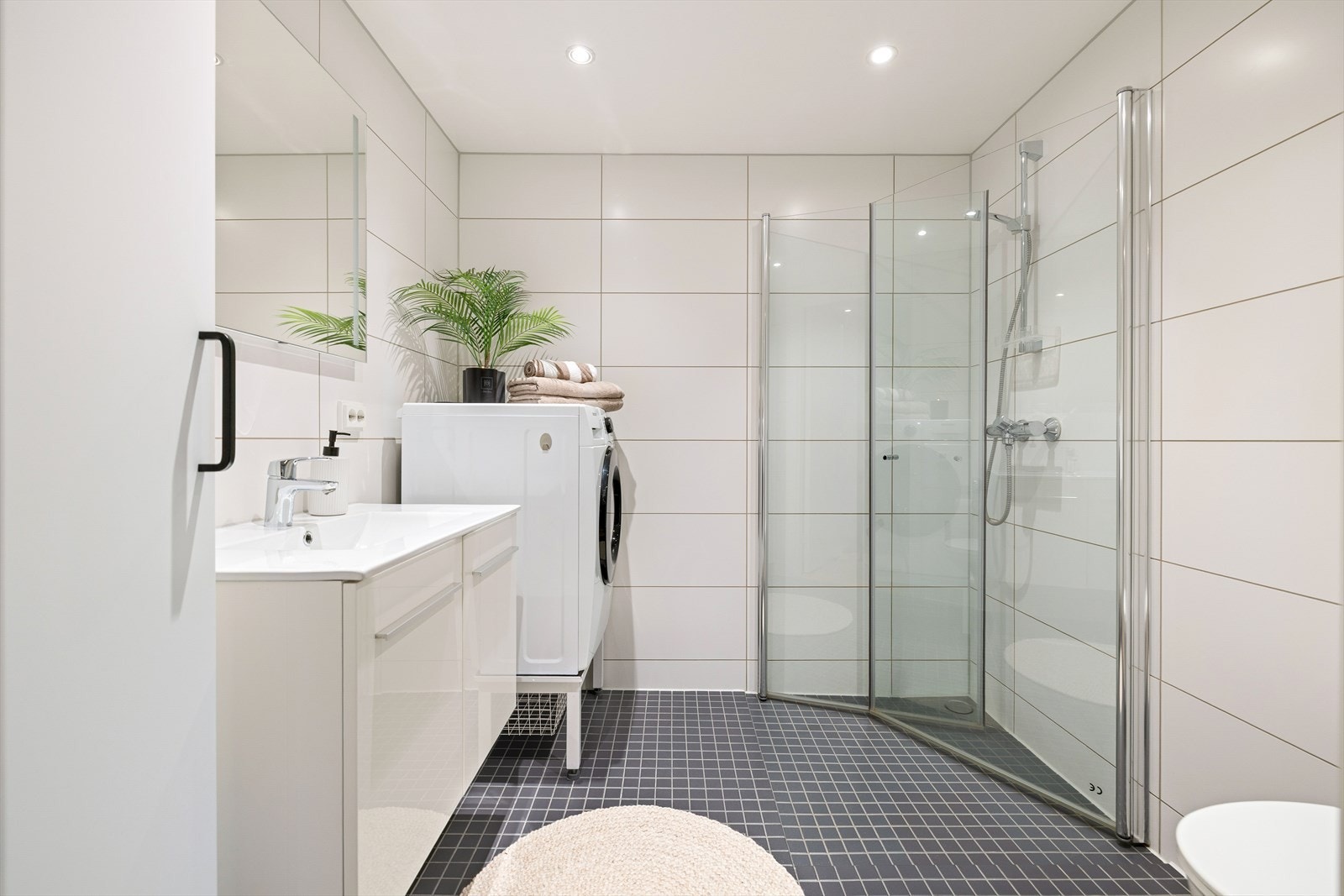 Det 4,5 m² delikate badet fremstår som innbydende med helflisede overflater, behagelig gulvvarme og downlights i tak. Galleribilde