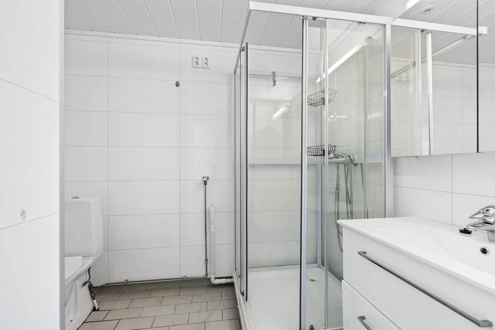 Badet har lys innredning med nedfelt servant og skuffer under, speilskap over, dusjkabinett, toalett og opplegg for vaskemaskin. Galleribilde