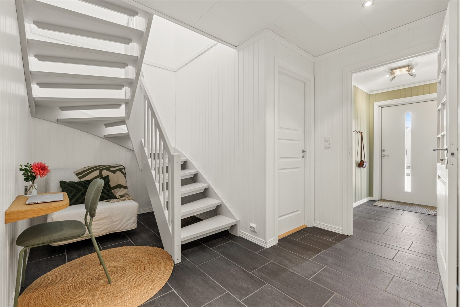 Entré med flislagt gulv og malt tretrapp som leder opp til andre etasje. Galleribilde