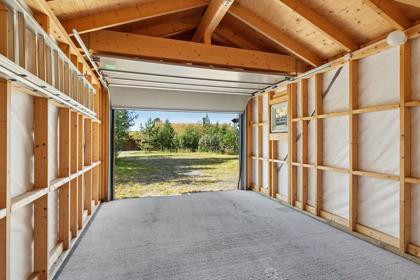 Frittliggende garasje fra 2010 med støpt betongplate, leddport og romslig bod Galleribilde
