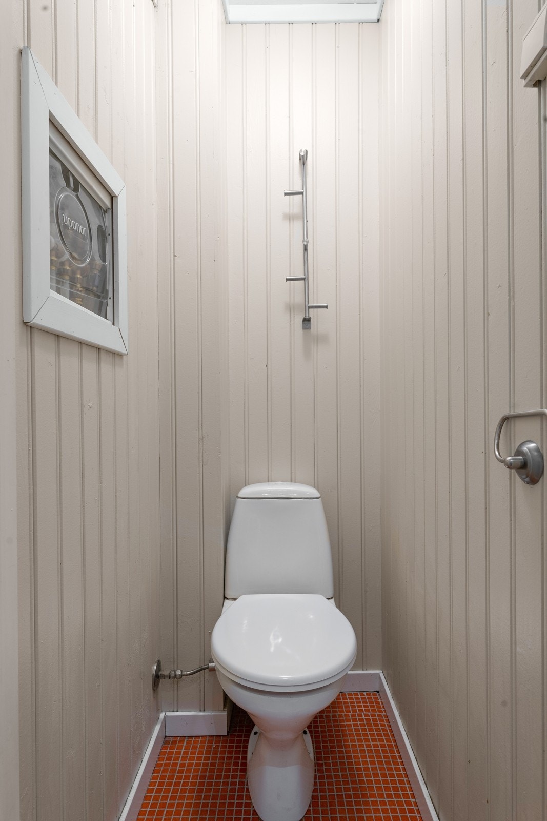 Praktisk toalettrom med flislagt gulv og panel på veggene. Galleribilde