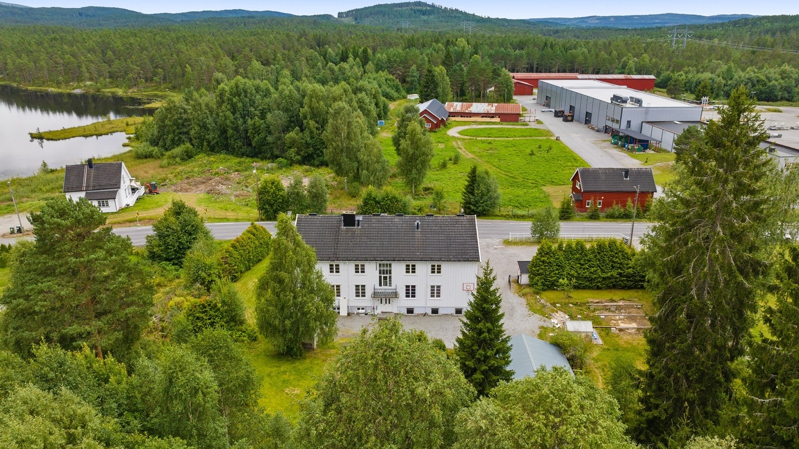 Eiendommen er pent opparbeidet med gruset gårdsplass, plenarealer og diverse beplantning Galleribilde