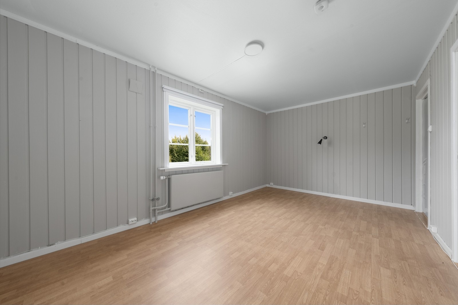 Lyst og trivelig rom i kontorfløyen i 1. etasje med panel på veggene og laminat på gulvet. Galleribilde