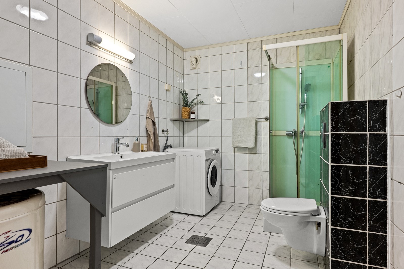Helfliset bad med vegghengt toalett, dusjhjørne og opplegg for vaskemaskin. Galleribilde