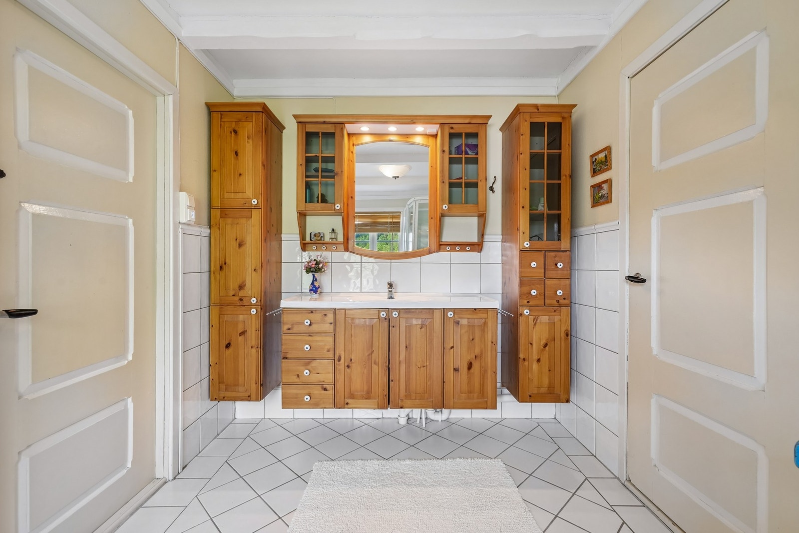 Badet har flislagt gulv, innredning med fronter i tre, med speil og god oppbevaringsplass. Galleribilde