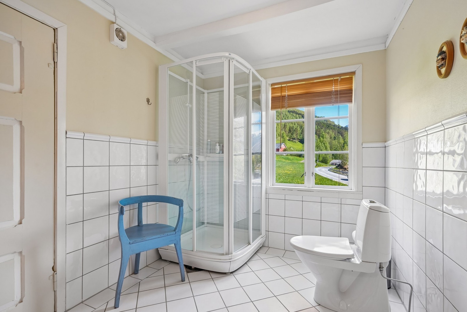 Lyst bad med dusjkabinett, toalett, flislagte vegger og gulv. Utsikten kan nytes selv fra badet. Galleribilde