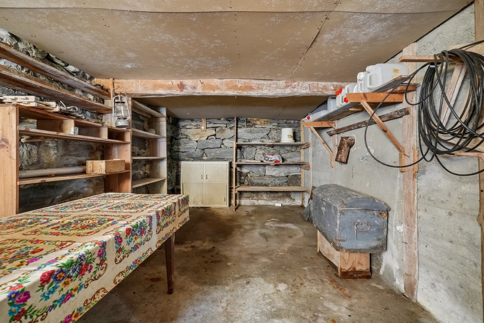 Kjellerrom med steinvegger, hyller og bord. Galleribilde