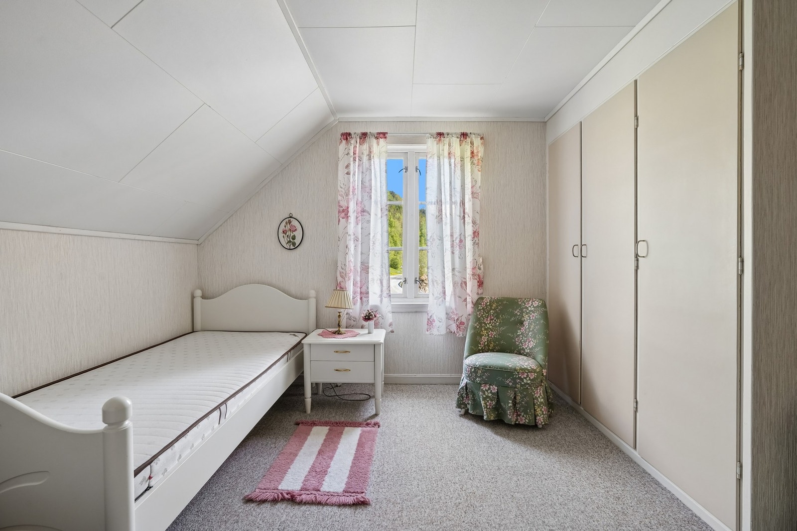 Lyst soverom med skråtak og plassbygde garderobeskap. Galleribilde