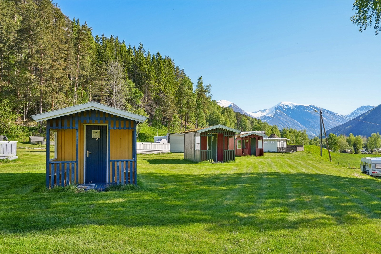 Flere små hytter på en åpen gresslette. Disse må renoveres for å benyttes videre til utleie. Galleribilde