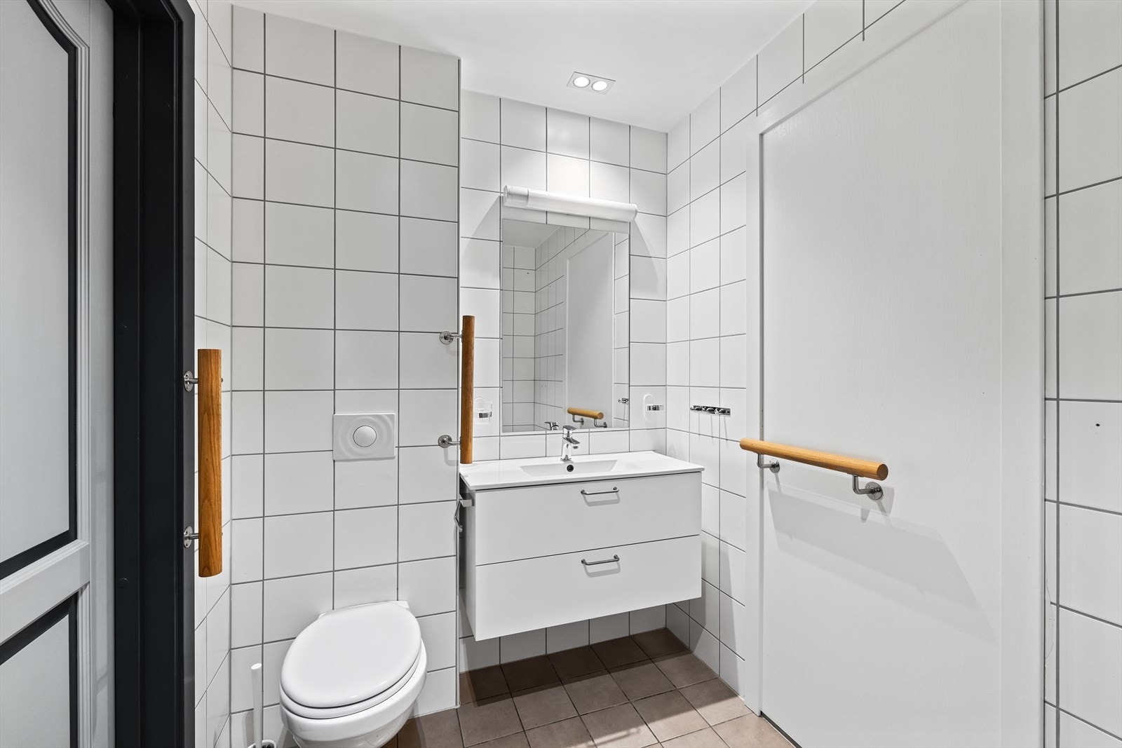 Det siste badet er lyst og pent utført, med flislagte overflater, servantinnredning med skuffer og vegghengt toalett. Galleribilde