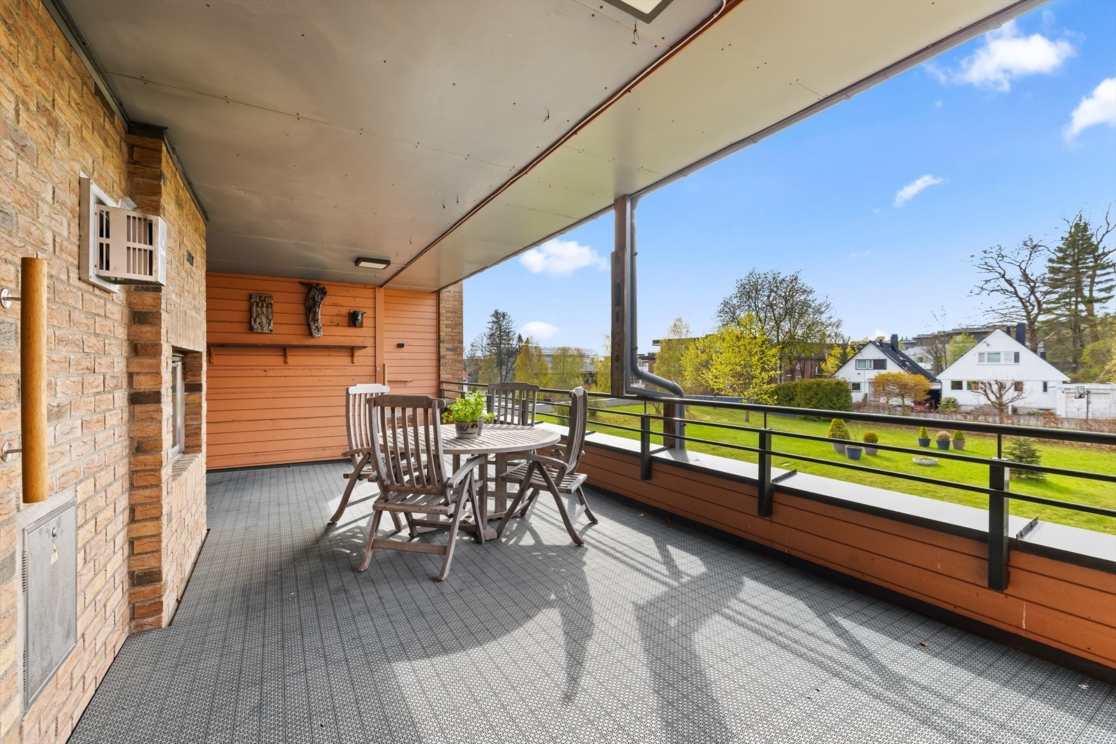 Terrassen har et åpent utsyn mot frodige grøntarealer og den omkringliggende villabebyggelsen. Galleribilde
