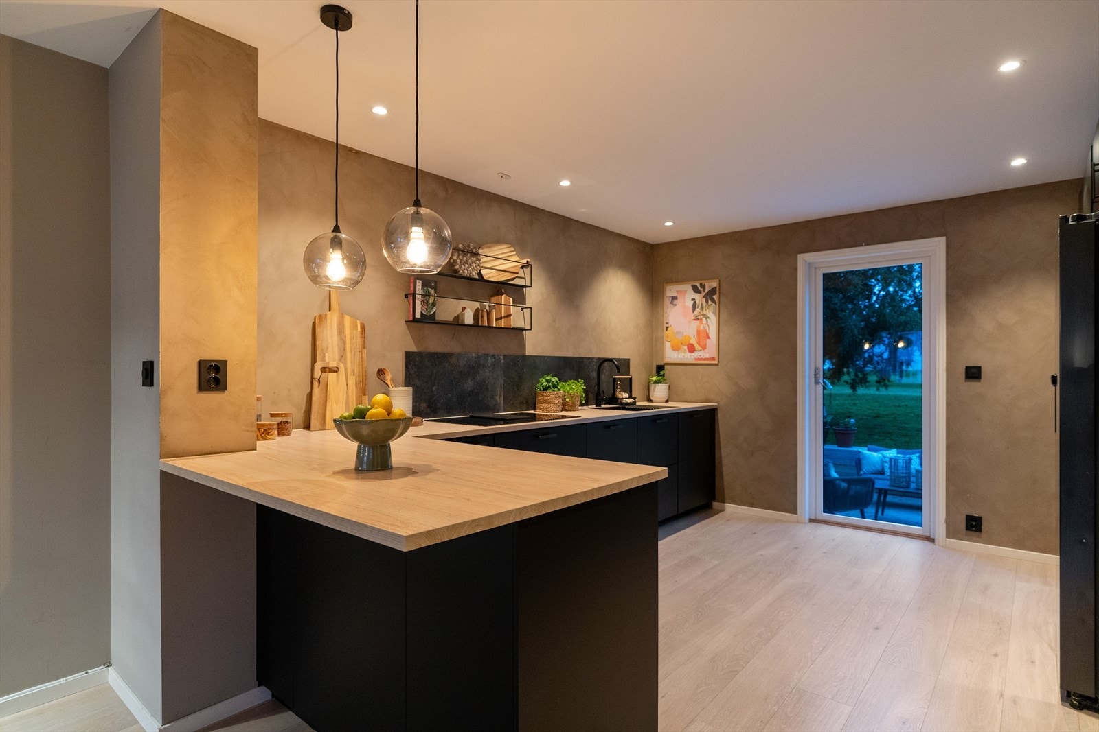 Kjøkkenet på 15 m² har god belysning fra dimbare downlights i himlingen. Veggen på kjøkkenet er malt med kalkmaling i den moderne fargen Marrakesh, som gir rommet et varmt og elegant uttrykk. Galleribilde