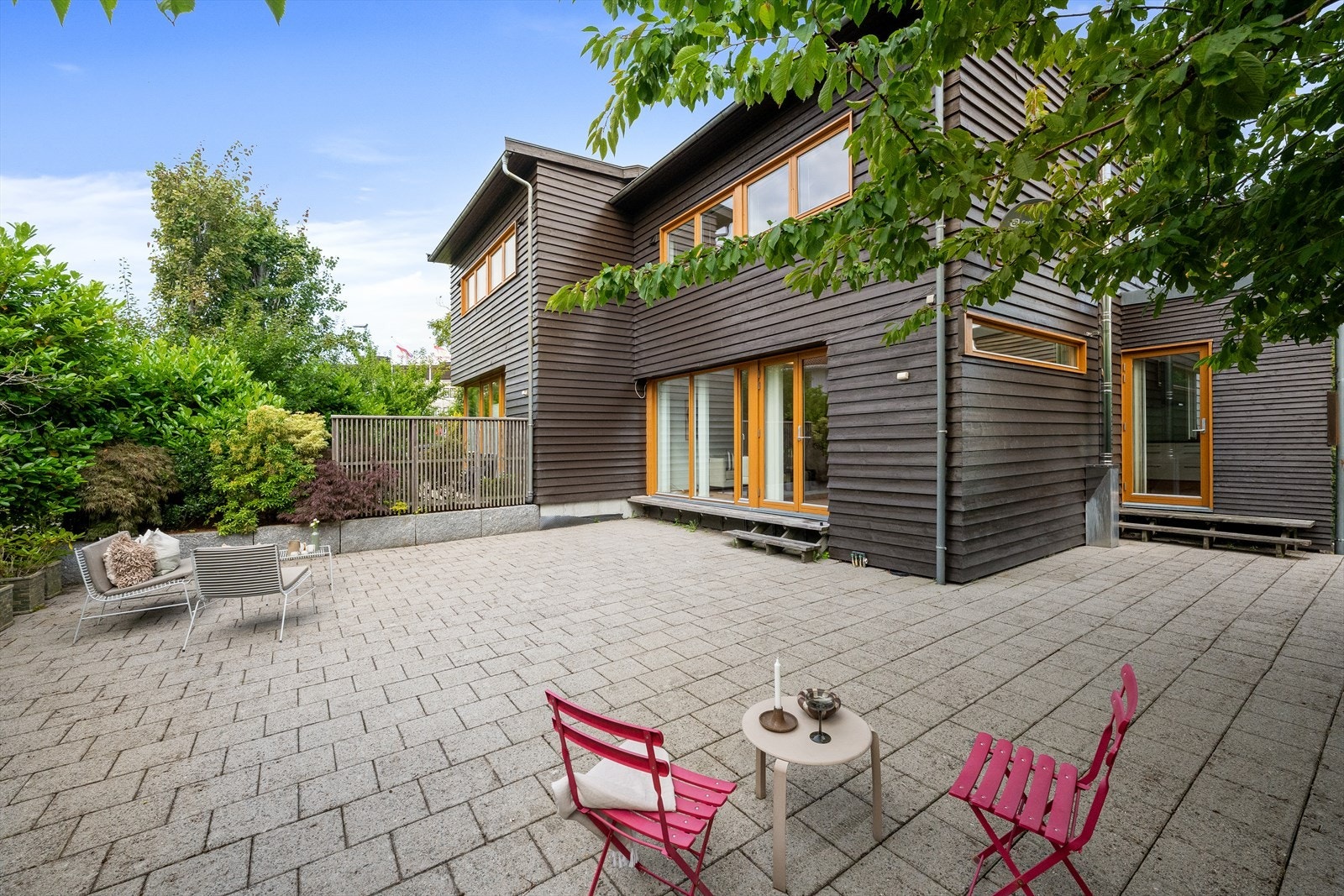 Uteplassen er lagt med betongheller og omkranset av frodig beplantning. Galleribilde