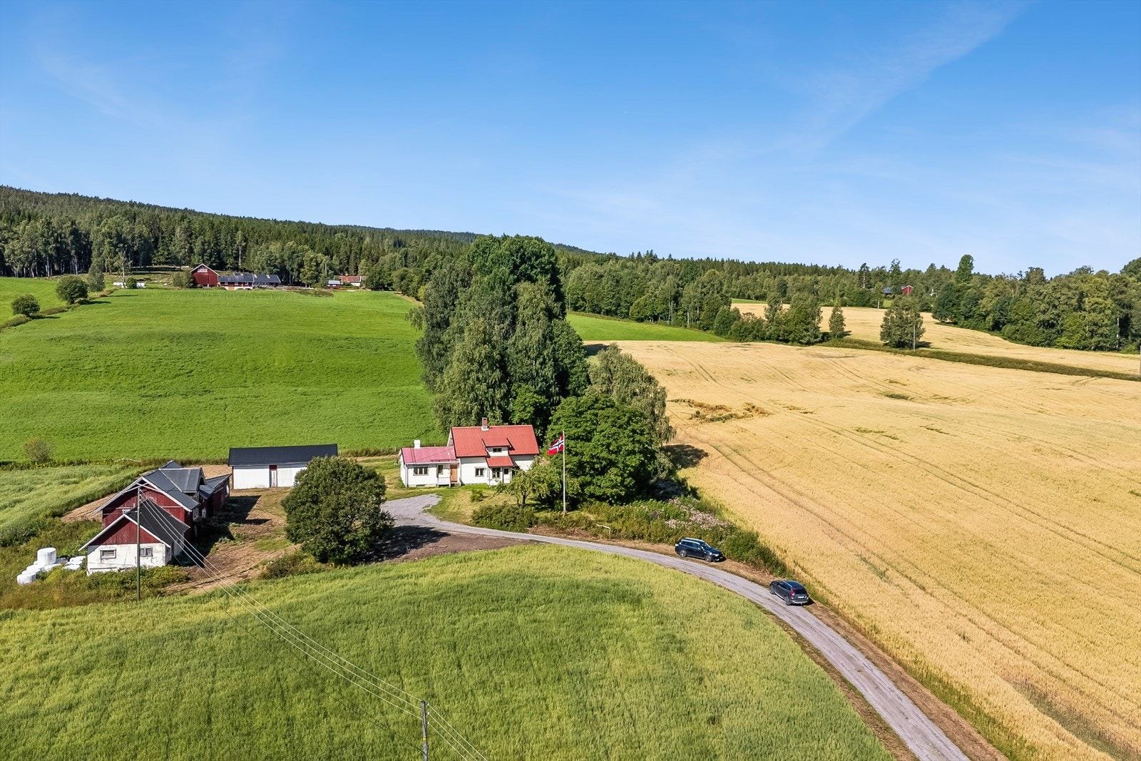 Oversikt over eiendommen med enebolig, låve og garasje. Galleribilde