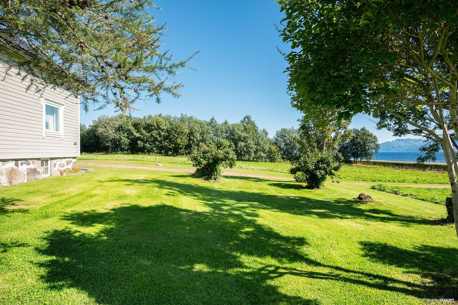 Stor og flat gressplen omkranser boligen. Galleribilde